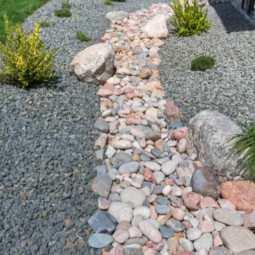 decorative dry creek bed with river rocks and surrounding gravel landscaping