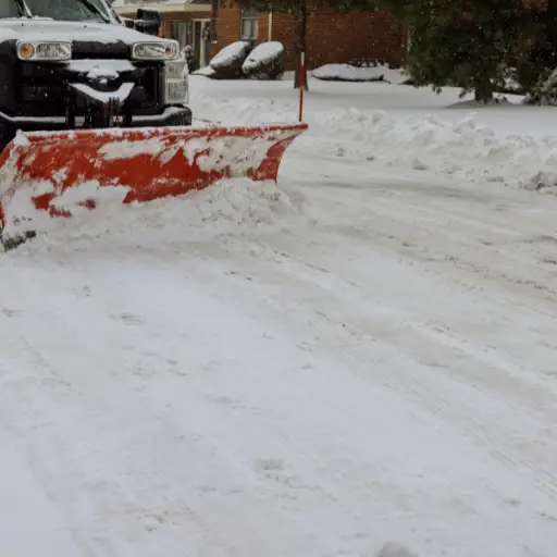 truck with snowplow clearing a residential street after heavy snowfall
